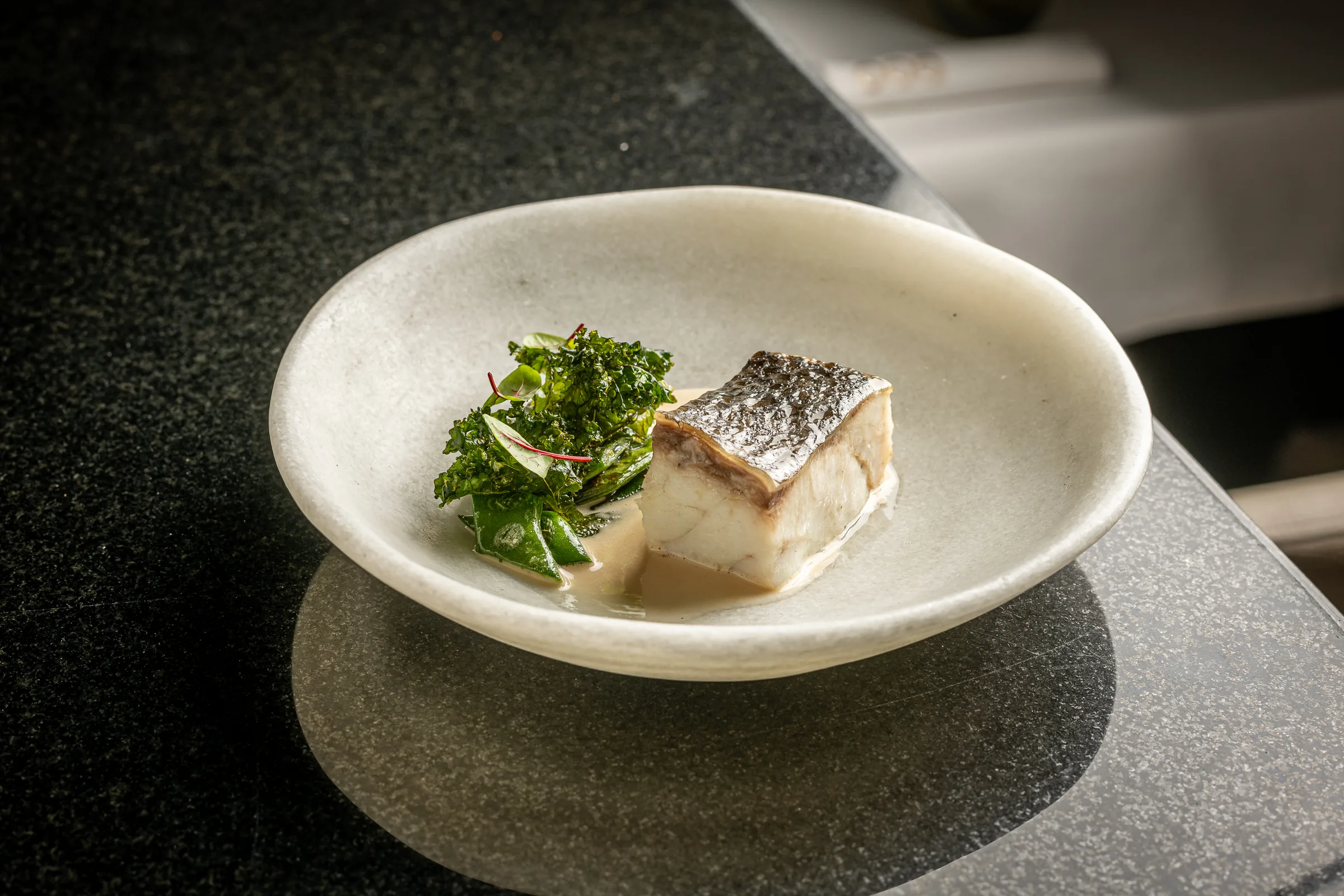 Corvina a la brasa con salsa de mantequilla e ibérico y bajocas, en Por Herencia